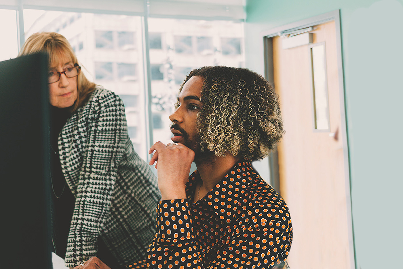 Doctor Sheryl Kubiak, a white woman, pays attention to a brown-skinned man as he looks at a computer.